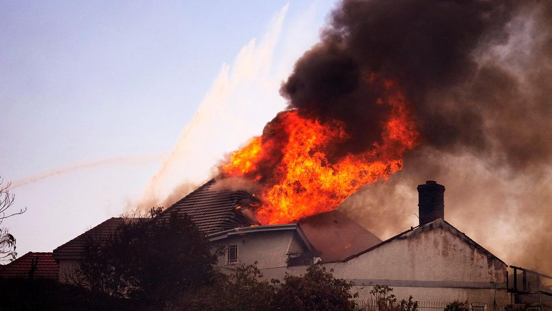High winds spark fast-moving Southern California wildfire that razes homes and forces mass evacuations